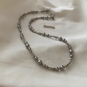 Detailed close-up of a French vintage pearl and geometric bead necklace on white fabric