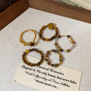 Détail de bagues vintage faites main en perles d'œil de tigre et jaspe sur bois