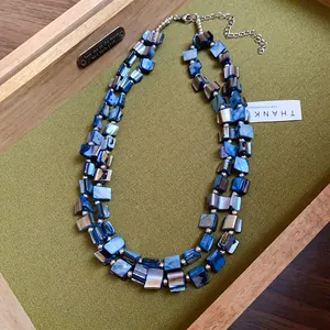 Close-up of bohemian double-layered necklace with iridescent blue shell fragments.