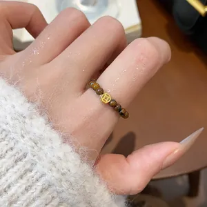 Vue rapprochée d'une bague en perles d'oeil de tigre avec un pendentif pièce vintage