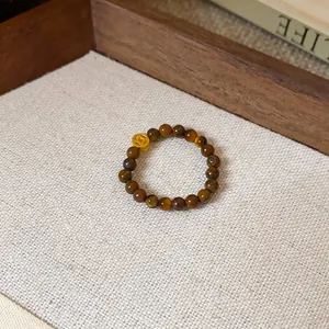 Vue détaillée d'une bague en perles d'œil de tigre ornée d'un charmant pendentif de pièce