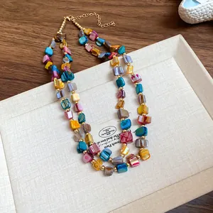 Close-up detail of a colorful bohemian irregular double-layered shell necklace on a tray
