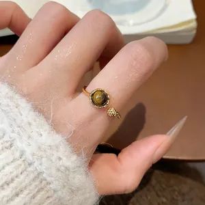 Gros plan détaillé d'une bague ouverte en or vintage avec une pierre œil de tigre polie