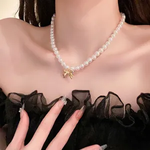 Elegante collana di perle in stile francese con ciondolo a fiocco dorato su modella
