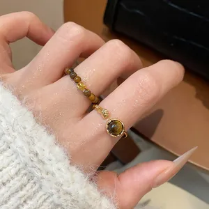 Détail d'une bague vintage en perles d'œil de tigre et d'une bague dorée ouverte
