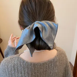 Detail of large grey leather scrunchie on brown hair with elegant retro style