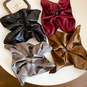 Macro detail of four vintage faux leather square scrunchies in various chic colors.