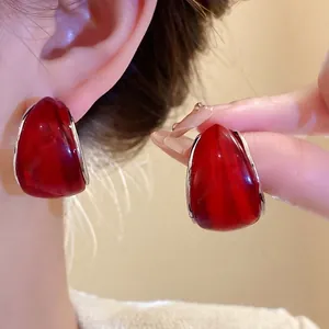 Elegantes pendientes de aro minimalistas en forma de C de resina roja con bordes plateados.