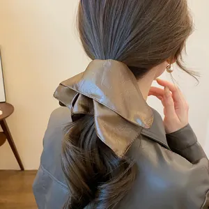 Close-up detail of a vintage brown leather square scrunchie tied on a low ponytail.
