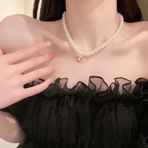 Dettaglio di un'elegante collana di perle francese con un ciondolo a fiocco dorato.
