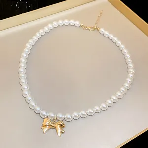 Dettaglio collana di perle elegante con ciondolo a fiocco dorato lucido per un look chic