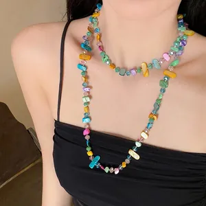 Dettaglio di una collana a più strati con pietre di vetro colorate indossata da una modella