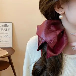 Close-up of a burgundy faux leather bow hair scrunchie on a ponytail