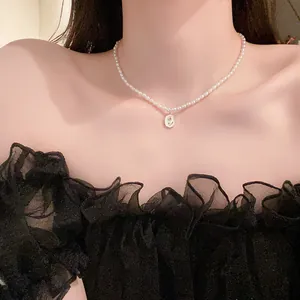 Primo piano di girocollo con perle barocche e ciondolo a forma di rosa