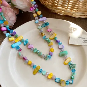 Dettaglio di una collana multistrato con perle di vetro colorate irregolari su un piatto