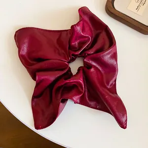 Close-up of a premium wine red leather scrunchie with a unique square pleated design