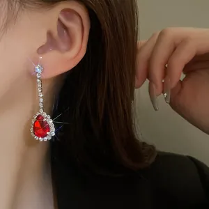 Vista dettagliata di eleganti orecchini a goccia con una gemma rossa e strass brillanti