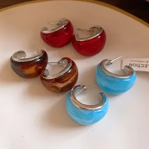 Detalle de los pendientes de aro de resina en colores rojo, ámbar y azul claro