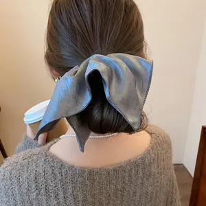 Elegant close-up view of a grey leather bow scrunchie worn on a model's ponytail