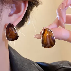 Vista detallada de pendientes de resina ámbar en forma de C con textura translúcida