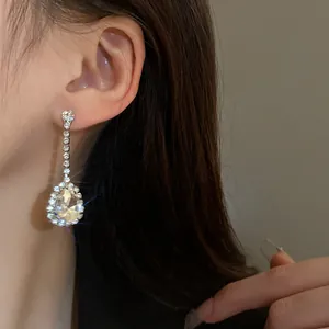 Primo piano di eleganti orecchini pendenti a goccia con strass indossati da modella