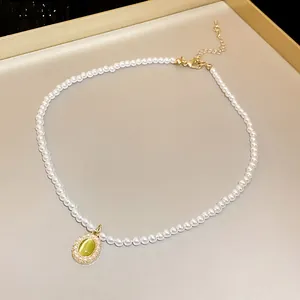 Primo piano di un'elegante collana di perle con ciondolo ovale in pietra occhio di gatto.