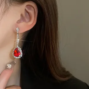 Primo piano di un lungo orecchino pendente con una pietra preziosa rossa a goccia