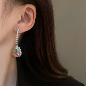 Primo piano di un orecchino a goccia di lusso con pietra iridescente su una modella