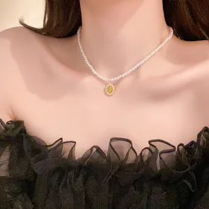 Dettaglio della collana di perle barocche con pendente a gemma gialla ovale su modella asiatica