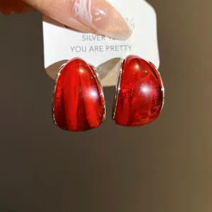 Primer plano de elegantes pendientes de resina roja con textura de mármol real