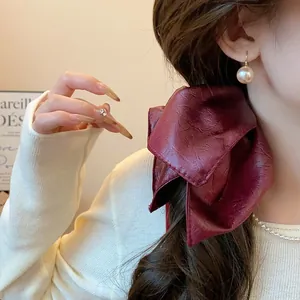 Detailed close-up showing the vintage texture of a burgundy leather hair scrunchie