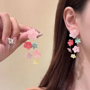 Dettaglio di orecchini pendenti con fiori e perline indossati dal modello