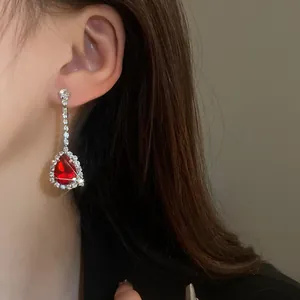 Primo piano di un elegante orecchino in argento con una gemma rossa a goccia