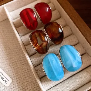 Vista detallada de pendientes vintage de resina en forma de C en colores rojo, ámbar y azul
