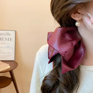 Detailed view of a vintage burgundy faux leather bow scrunchie styled on a ponytail