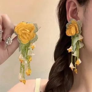Dettaglio di orecchini pendenti a fiori con perline stile foresta su modella asiatica