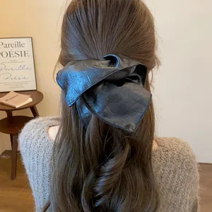 Close-up of a vintage-style black leather square scrunchie on long brown wavy hair