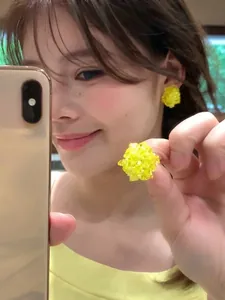 Vista ravvicinata di una modella che indossa orecchini a bottone a fiore di perline gialle