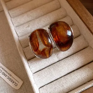 Primer plano de pendientes vintage de resina en forma de C con textura de ámbar