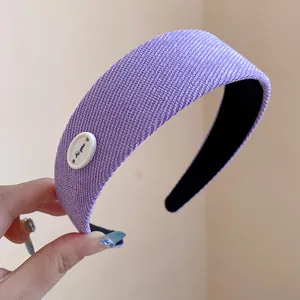 Dettaglio della trama in maglia viola e del bottone ovale bianco di questo cerchietto