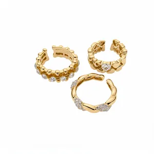 Set di tre anelli aperti dorati con decorazioni a cuore e cristalli brillanti.