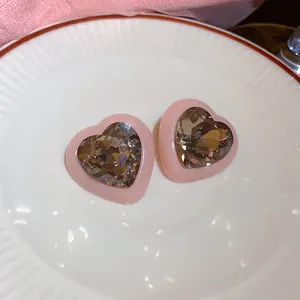 Detailweergave van roze hartvormige oorbellen met veelzijdige champagne kristallen