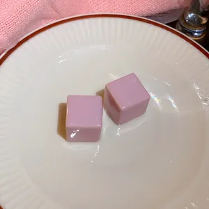 Detailopname van paarse kubusvormige oorknopjes op een wit keramisch bord