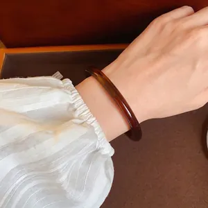 Vintage wide amber acrylic geometric bangle bracelet worn on a stylish female wrist