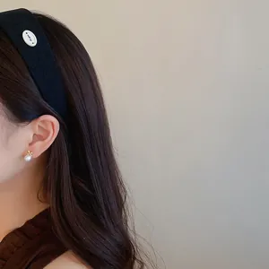 Dettaglio di un cerchietto elegante in tessuto nero a costine indossato da una modella