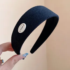 Primo piano di un cerchietto per capelli in tessuto nero con decoro ovale bianco elegante.