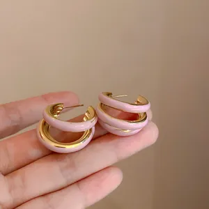 Close-up van roze geëmailleerde meerlaagse oorringen in de hand voor detailview