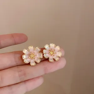 Detailopname van elegante roze bloem oorknopjes met glinsterende gouden randen en hartjes