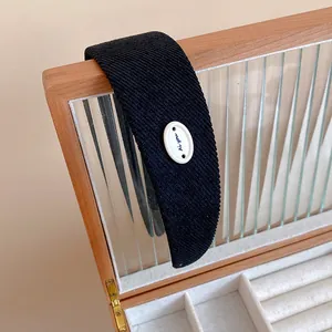 Primo piano di cerchietto in tessuto blu navy con bottone decorativo ovale bianco.