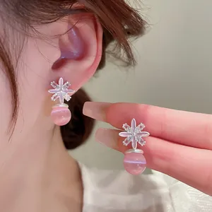 Detail van zilveren bloemoorbellen met roze kattenoogkralen en strass-steentjes